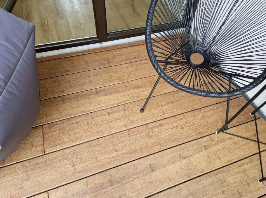 Verlegte Bambus-Terrassendielen in heller Sandfarbe auf einem modernen Balkon mit Sitzmöbeln.