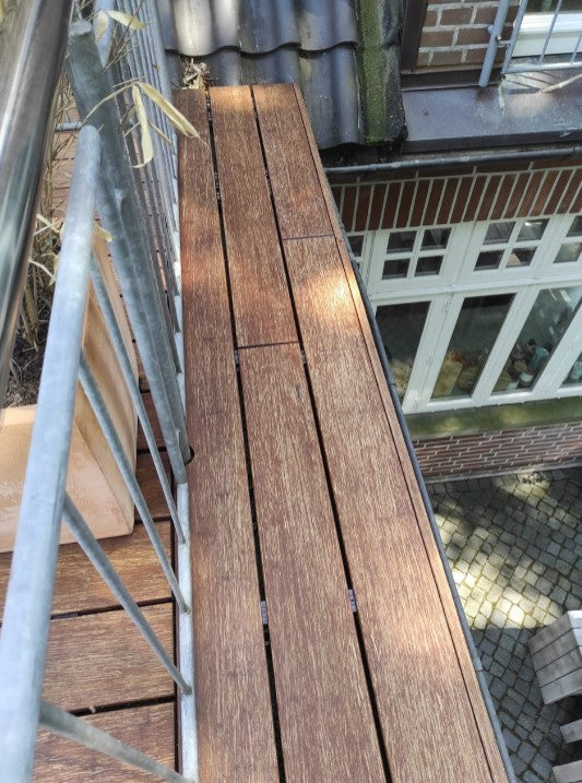 Blick entlang eines Balkonbodens aus Holz nach der Reinigung. Nach der Behandlung mit dem Anti-Belag-Reiniger, wirkt der Belag gleichmäßig sauber und frei von Algenbewuchs.