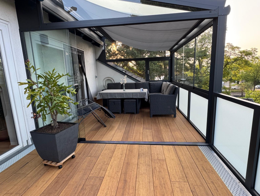 Die aMbooo Bambusdiele Cristobal unter moderner Überdachung an einem Einfamilienhaus, ausgestattet mit Gartenmöbeln. Nachhaltige Closed Decking Bambusdielen , ideal für stilvolle und wetterfeste Terrassengestaltung.