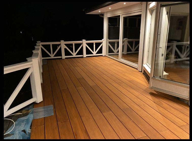 Moderne Terrasse mit glatten Bambus-Terrassendielen und weißem Geländer bei stimmungsvoller Abendbeleuchtung.