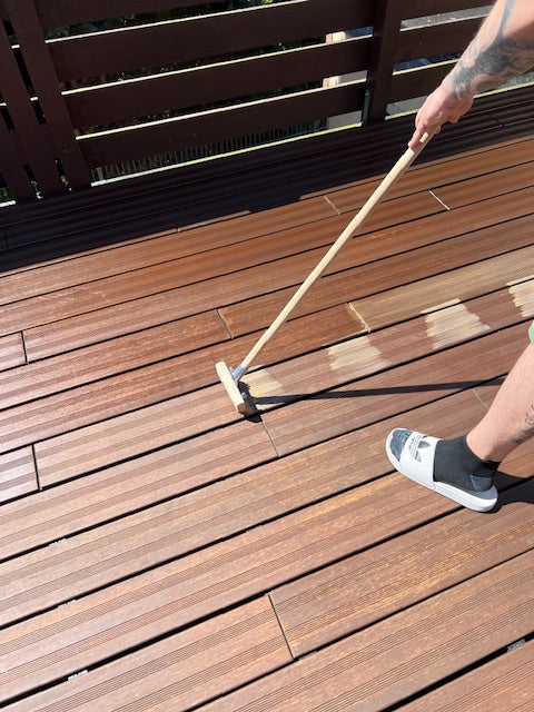 Terrassenöl wird mit einem Flächenstreicher gleichmäßig auf die Dielen einer Bambusterrasse aufgetragen, um die Oberfläche zu pflegen und vor Witterungseinflüssen zu schützen.