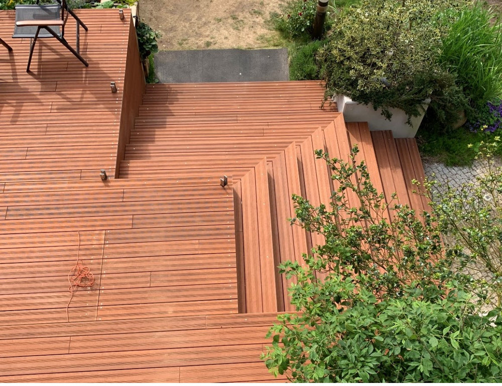 Mehrstufige Bambusholz-Terrasse mit integrierter Treppe und Podesten in einem Garten, aufgenommen aus der Vogelperspektive.