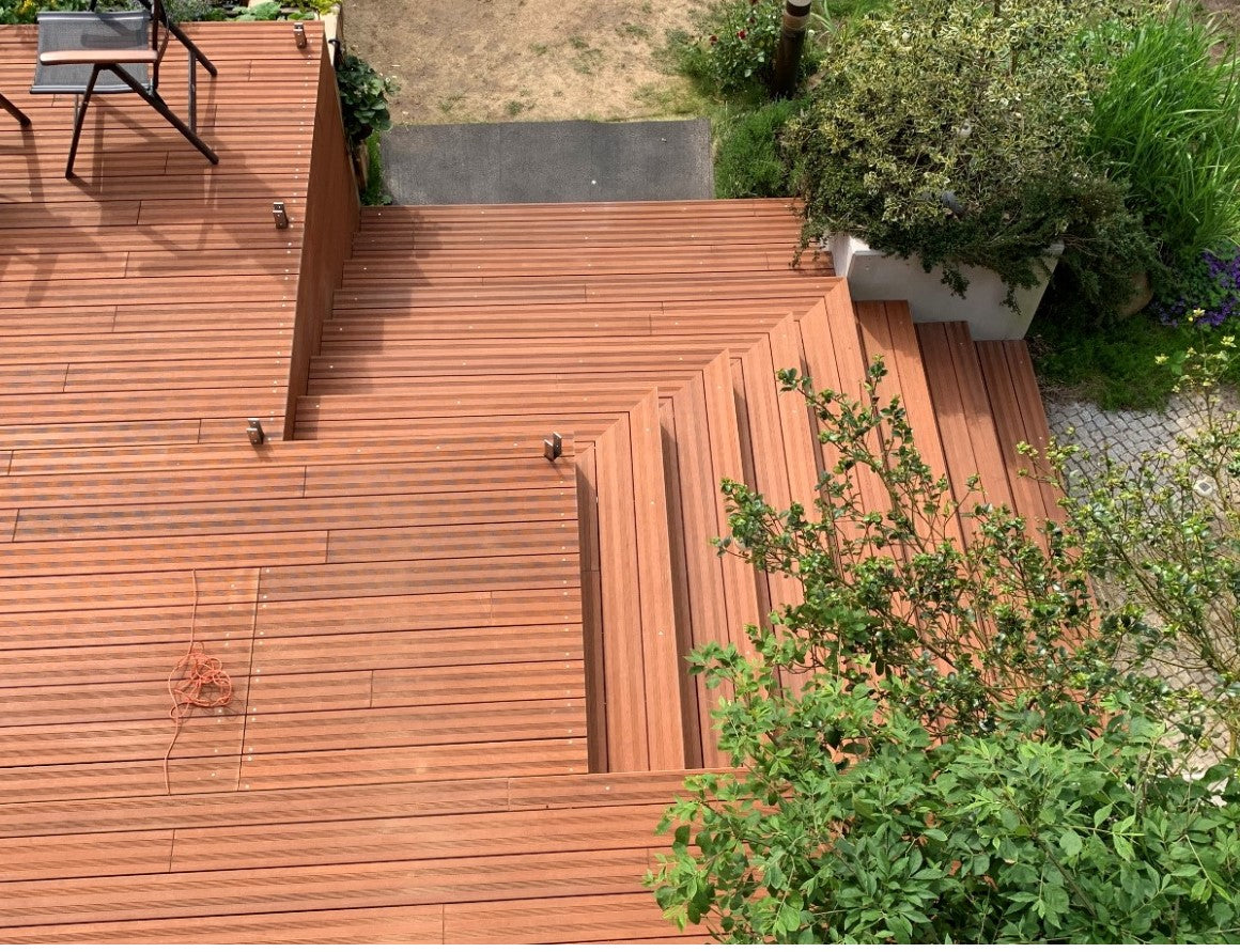Mehrstufige Bambusholz-Terrasse mit integrierter Treppe und Podesten in einem Garten, aufgenommen aus der Vogelperspektive.