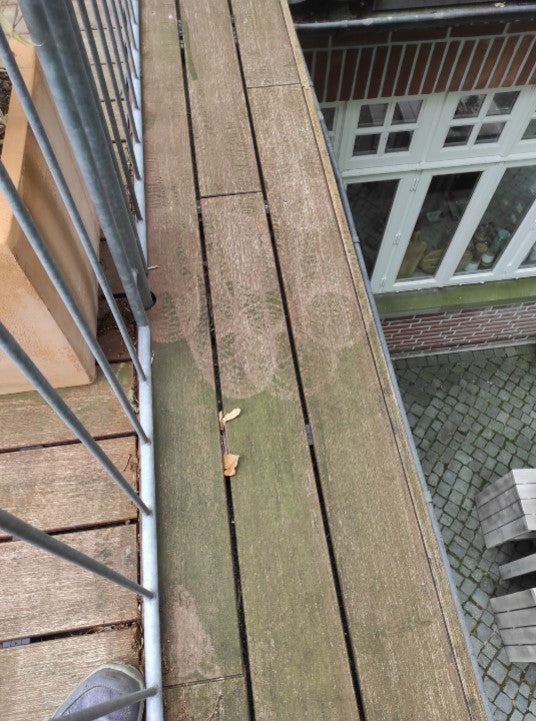 Bambus-Terrassendielen vor der Behandlung mit Anti-Belag-Reiniger. Sichtbare Algen- und Grünbeläge sowie Verschmutzungen auf der Terrassenoberfläche vor der Reinigung.