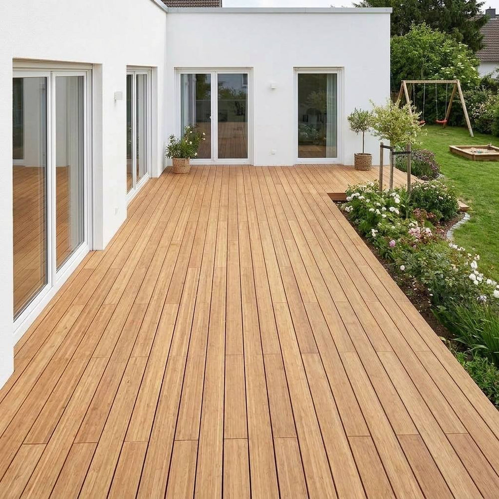 Großzügige Bambusholzterrasse vor einem weißen Wohnhaus mit Blick in den Garten.