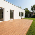 Große Closeddeck Bambusterrasse mit transparentem Metallgeländer an einem modernen weißen Wohnhaus mit Garten.