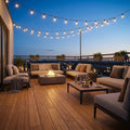 Großzügige Dachterrasse mit modernen Loungemöbeln, zentraler Feuerstelle, gedecktem Tisch und leuchtenden Lichterketten in der Abenddämmerung.