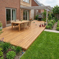 Großzügige helle Bambusterrasse mit Esstisch, Sitzgruppe und Pergola in einem begrünten Garten.