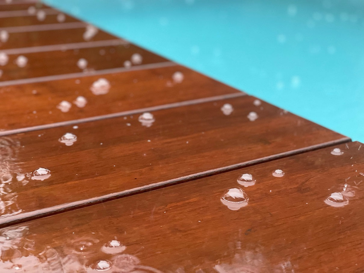 Nach dem einlassen mit dem Bambus Plegeöl perlt der Regen von der Terrassendiele ab. Nahaufnahme Bambus Terrasse am Pool im Regen.