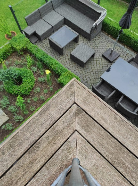 Detailansicht von vergrauten und verwitterten Terrassendielen auf einem Balkon .  Als vorher Bild für die Anwendung des AMBOOO Terrassen-Reinigers.