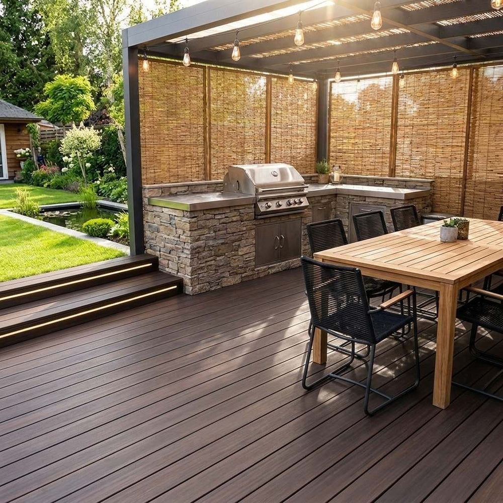 Überdachte Gartenterrasse mit dunklen Dielen, Outdoor-Küche samt Grill, großem Esstisch, Bambus-Sichtschutz und Lichterkette.