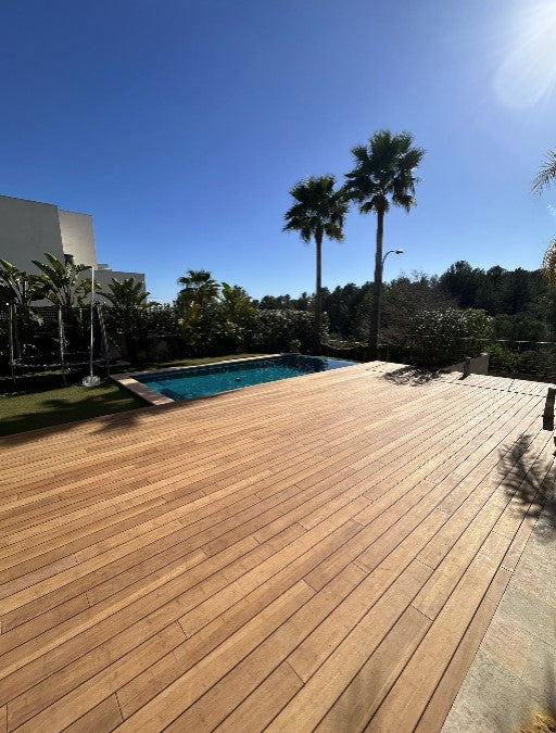 die aMBOOO Terrasse Campoverde am Pool verleget, mit Mediterranen Garten im Sonnenschein.