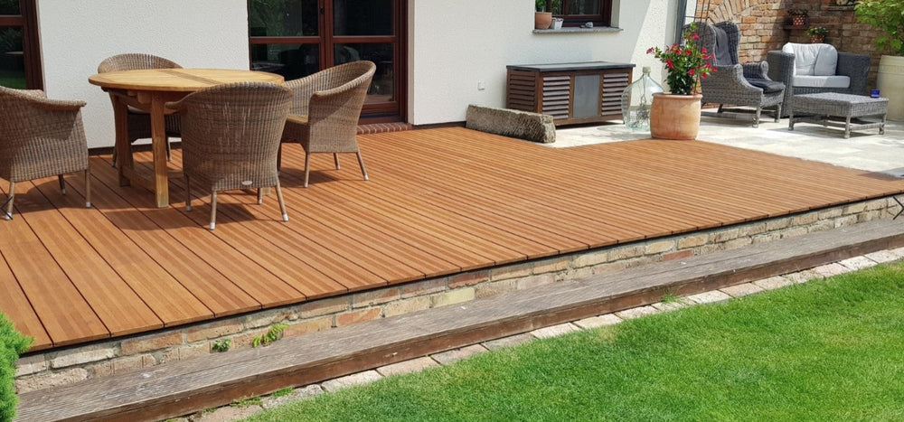 Großzügige Terrasse mit fein geriffelten Bambus-Terrassendielen Vinales, Gartenmöbeln und gepflegtem Rasen vor einem Wohnhaus.