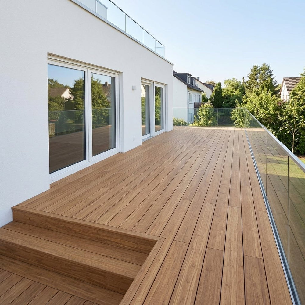 Großzügige Holzterrasse an einem modernen weißen Wohnhaus mit Glasgeländer und Blick ins grüne Wohngebiet.