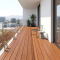 Moderner Balkon mit Holzdielen, Glasgeländer, Sitzplatz und Kübelpflanzen mit Blick über die Stadt.