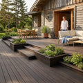 Großzügige Terrasse mit dunkelbraunen Bambus-Terrassendielen, integrierten Pflanzbeeten, Sitzlounge und Essbereich vor einem rustikalen Holzhaus.