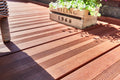 „Detailaufnahme einer hochwertigen Bambus-Terrasse mit geriffelter Oberfläche, dekorativer Pflanzkiste und Gartenmöbeln im Sonnenlicht.