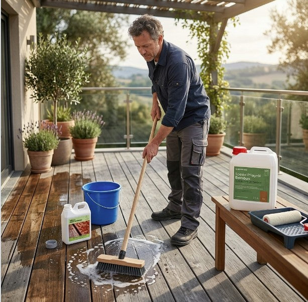 Person reinigt eine Holz- oder Bambusterrasse mit Bürste und Wasser eine aMBOOO Terrasse. Daneben stehen ein Eimer sowie Bambus-Pflegeprodukte zur Terrassenreinigung und -pflege. Die Szene zeigt die fachgerechte Reinigung und Pflege von Terrassendielen zur Erhaltung der natürlichen Holzoptik und Langlebigkeit im Außenbereich.