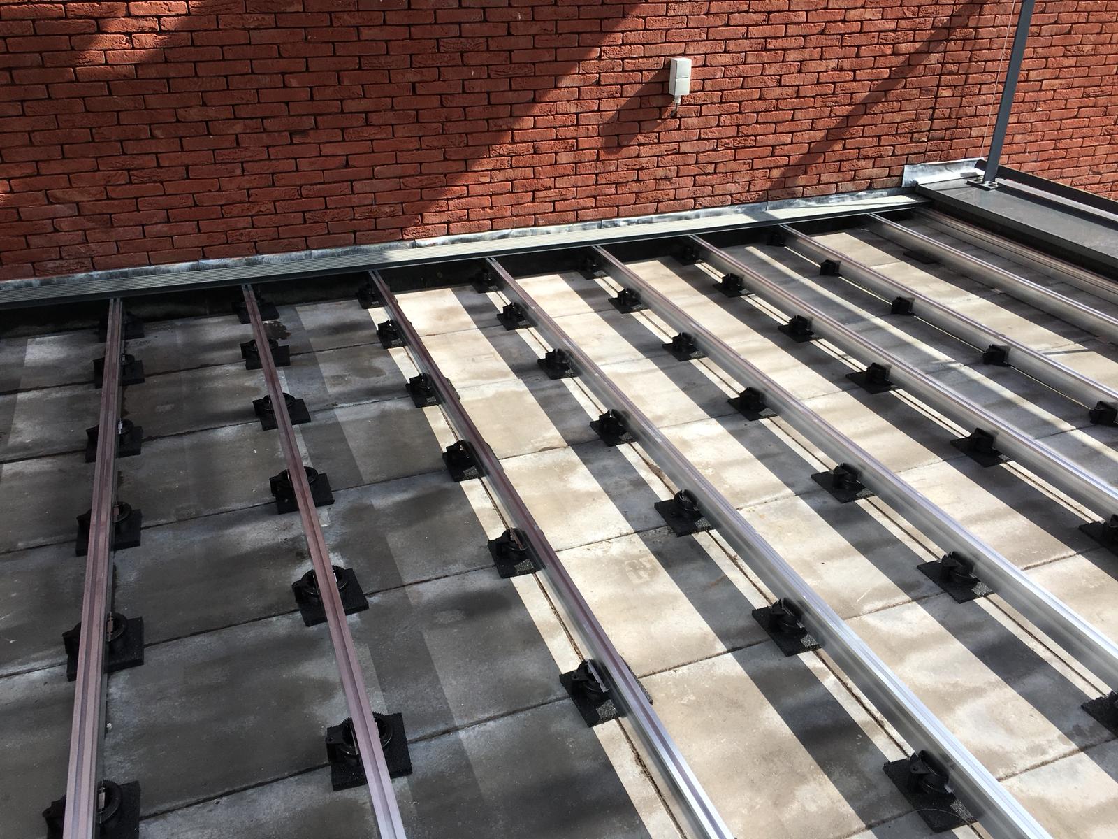 Aluminium-Unterkonstruktion für eine Dachterrasse auf Stelzlagern und Betonplatten als Basis für ambooo Terrassendielen.