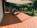 Moderne Terrasse mit Markise, Sitzgruppe und Blick auf einen liebevoll angelegten Garten an einem sonnigen Tag.